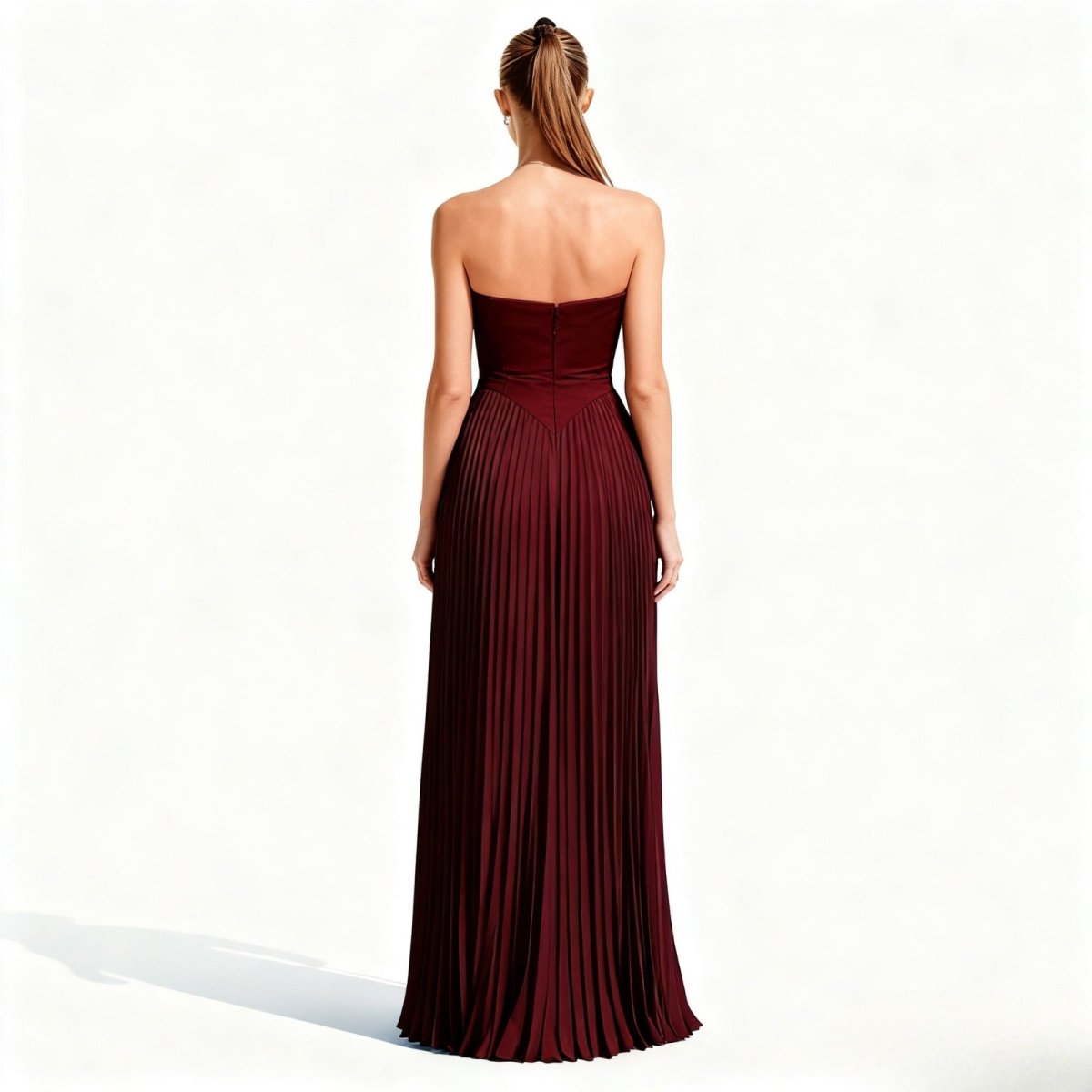 Woman wearing a burgundy kouvr strapless gown on a white background