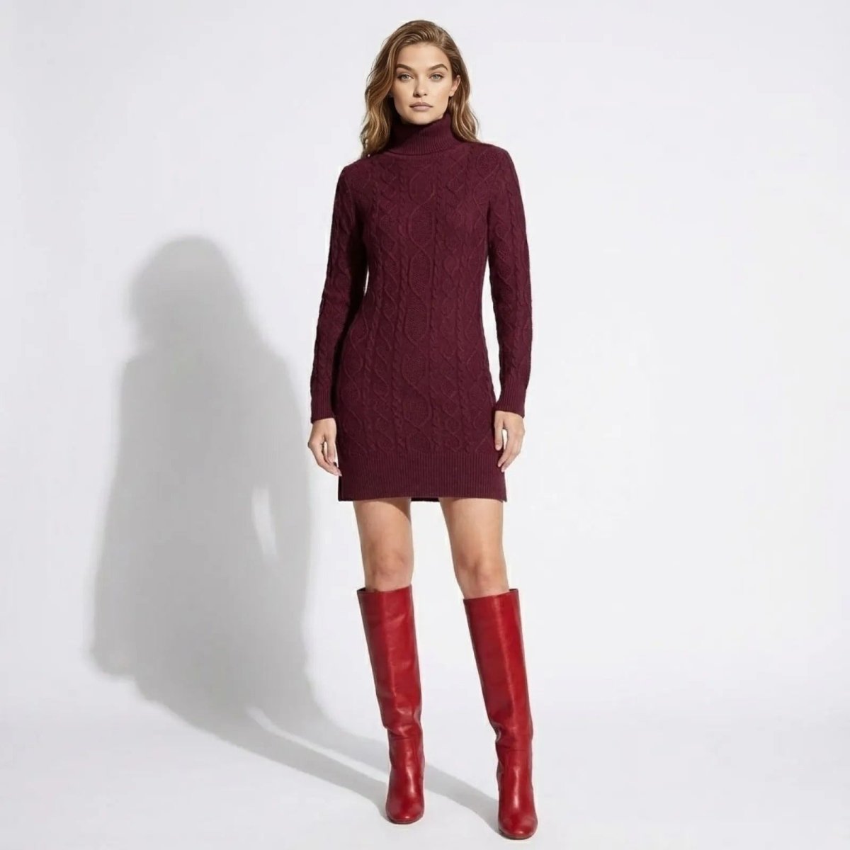 Model wearing the Kouvr Fashion burgundy cable-knit turtleneck sweater dress with long sleeves, paired with red knee-high boots, shown from the front.
