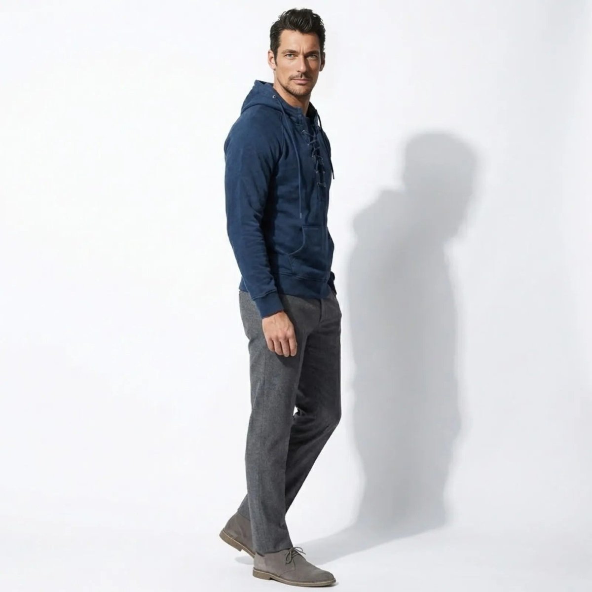 Side profile of a male model wearing the Kouvr blue pullover hoodie, showcasing the tailored fit and raglan sleeves.