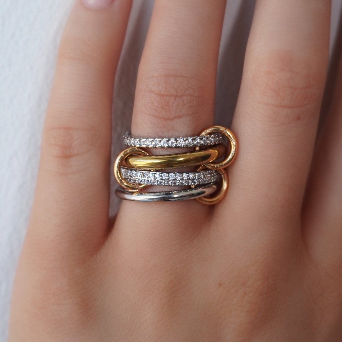 Kouvr gold and silver rings with diamond accents on a finger against a white background