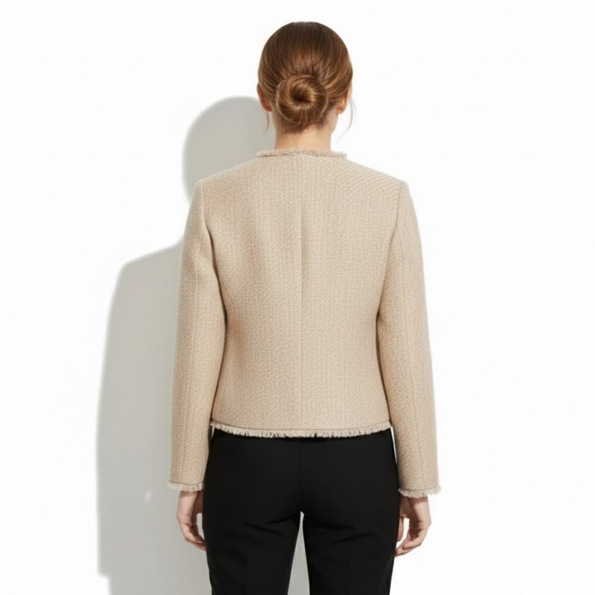 Back view of a model wearing the Kouvr tailored beige tweed jacket, showcasing the clean lines and structure.