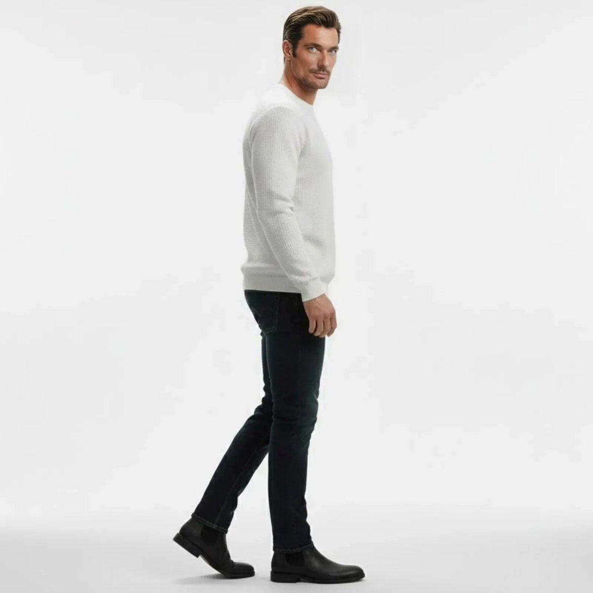 Man in profile wearing Kouvr's chalk white textured sweater, showing the slim fit and arm detail.