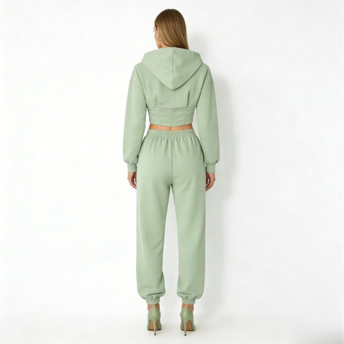 Back view of the Kouvr green sweatsuit, highlighting the corset boning detail on the hoodie and the fit of the fleece joggers.