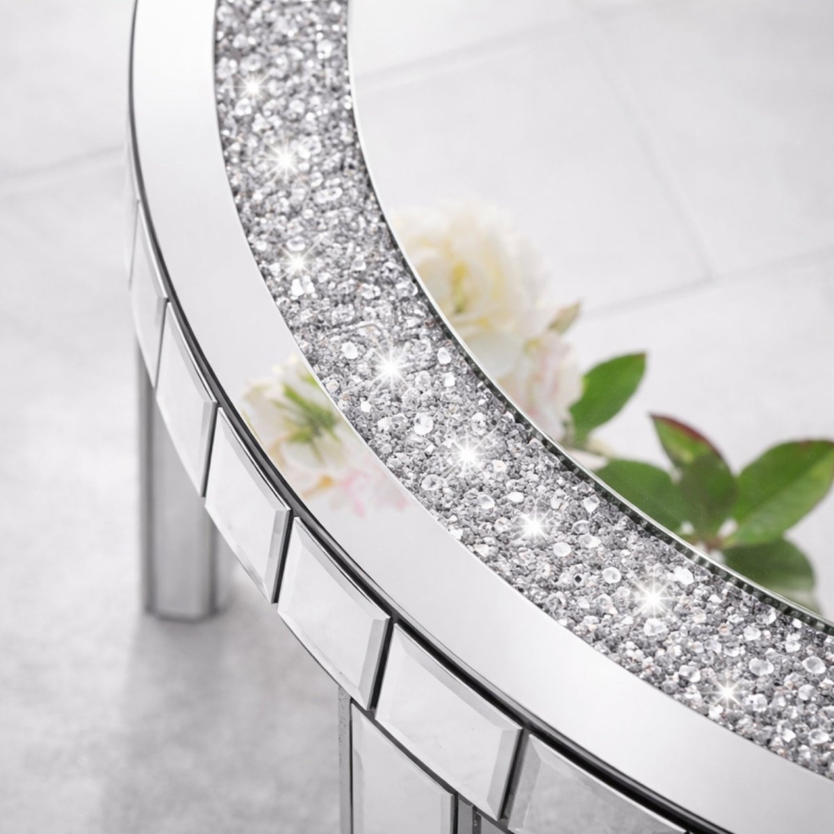 A close-up detail shot of the sparkling crushed diamond and crystal inlay on the border of the round mirrored coffee table.