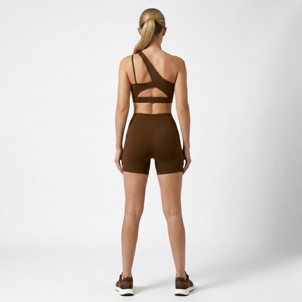 Back view of Kouvr dark brown activewear set highlighting strappy cutout sports bra and high waisted shorts