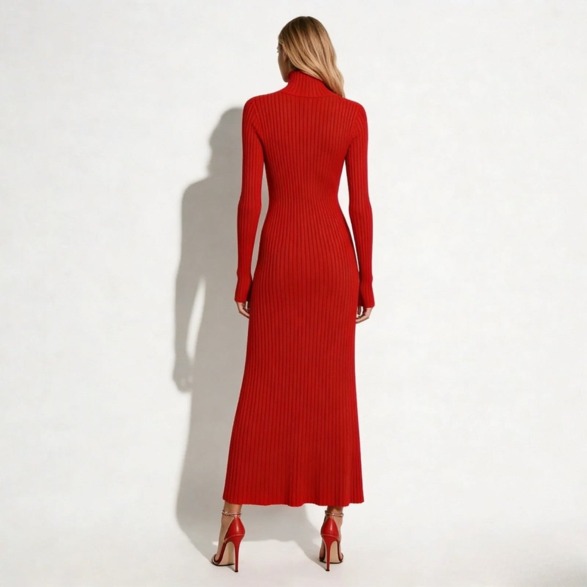 Back view of the long sleeve poppy red turtleneck dress by Kouvr, showing the continuous vertical ribbing that elongates the figure.