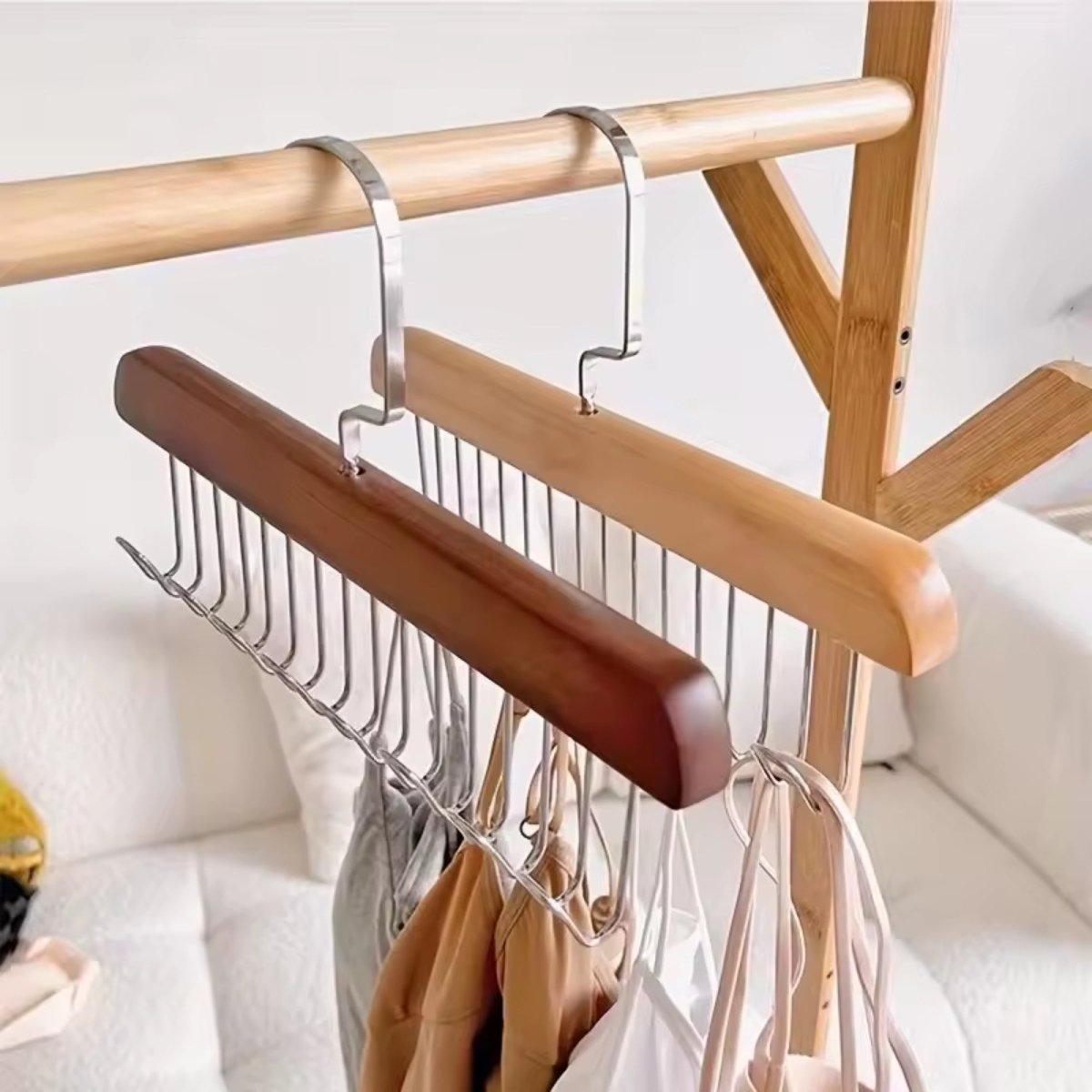 High angle view of two Kouvr wooden closet hangers showing the space-saving dual-sided metal hook layout holding clothing straps.