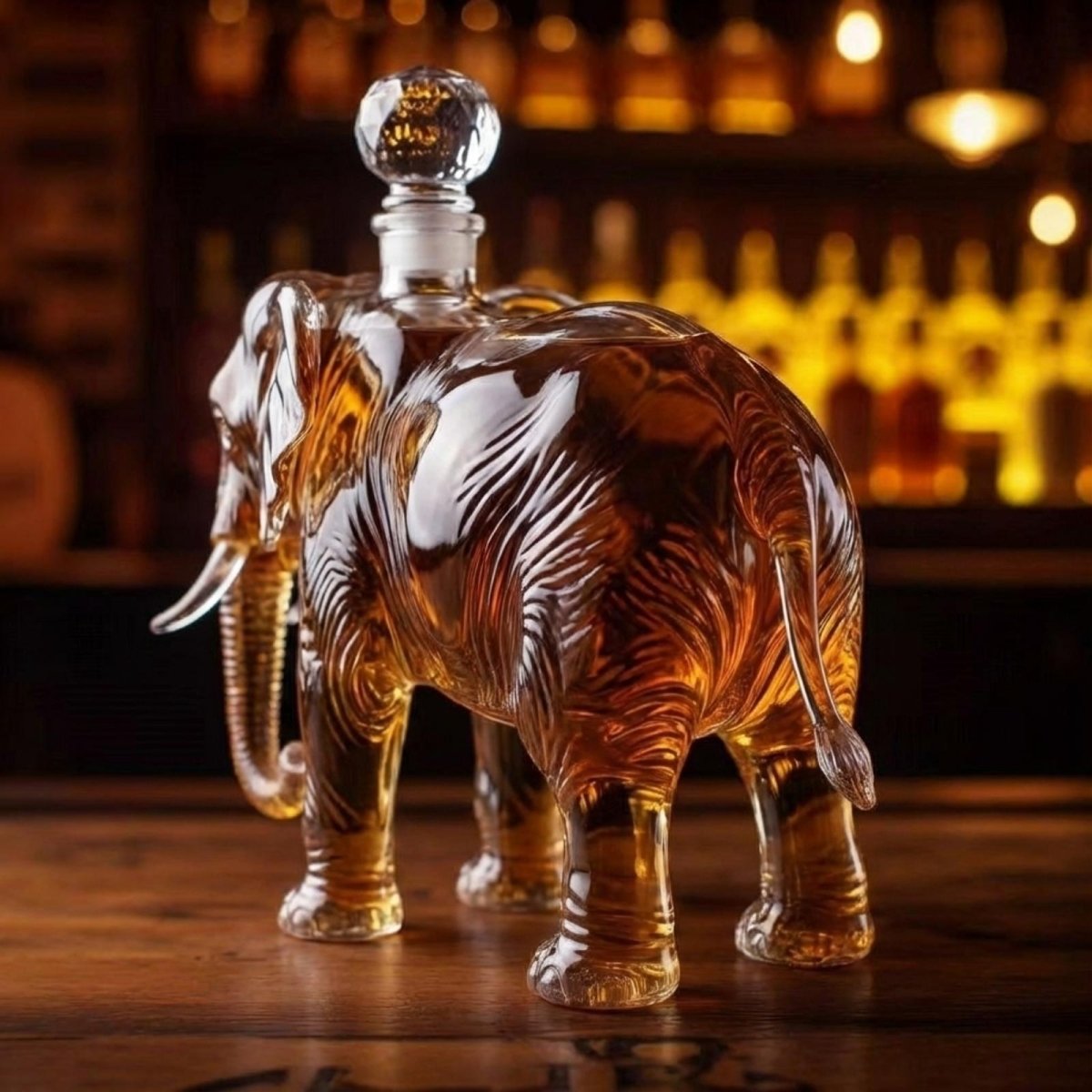 Rear three-quarter view of the Kouvr elephant liquor decanter, highlighting the curved glass details and the elegant glass stopper on a bar counter.