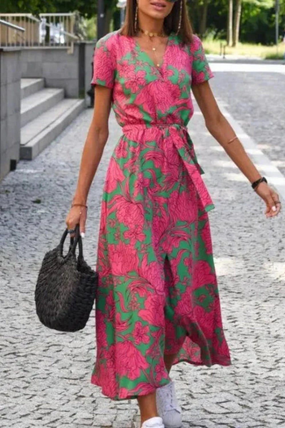 Model wearing Kouvr Fashion pink floral midi wrap dress walking on a cobblestone street