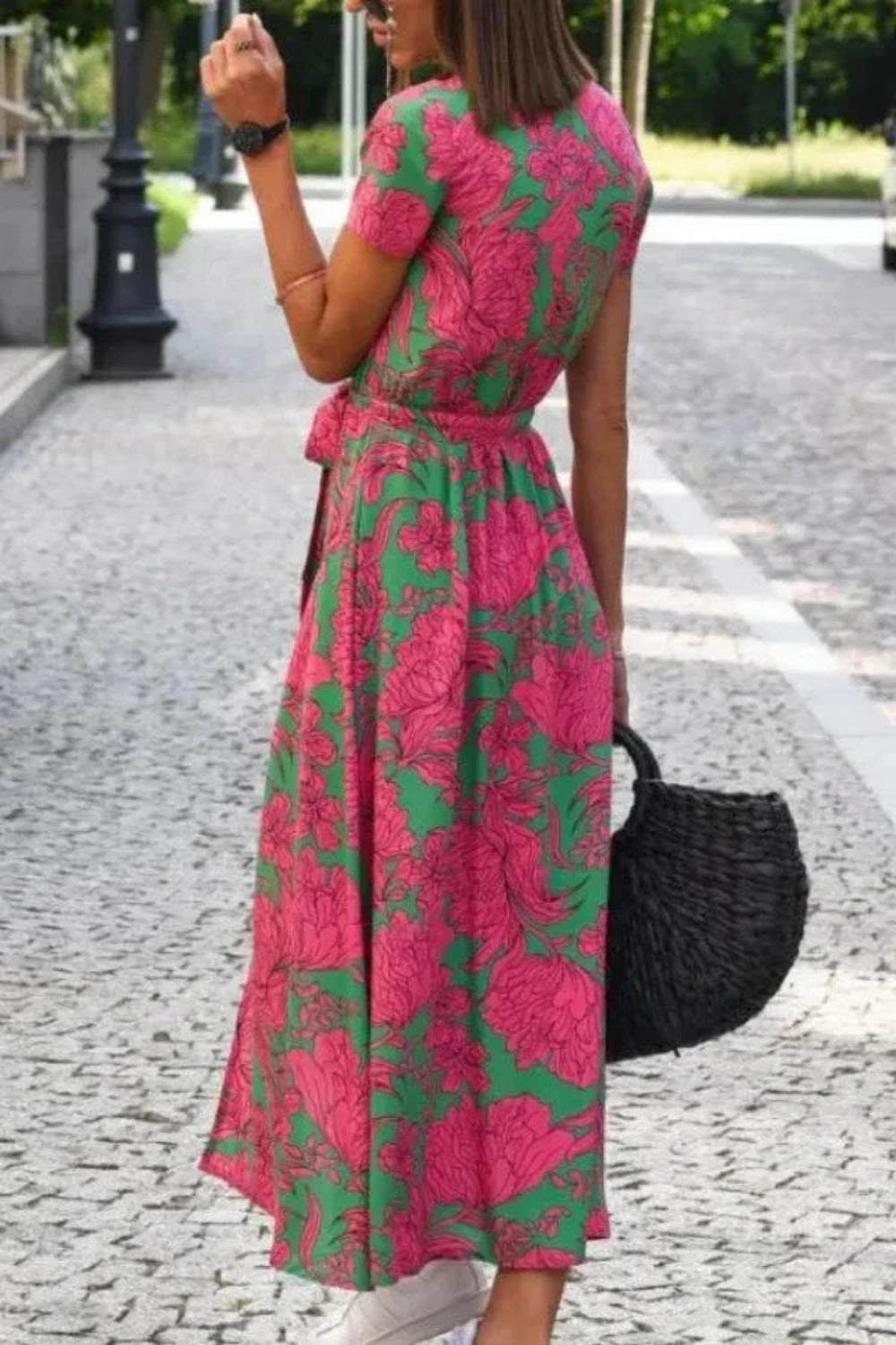 Model wearing Kouvr Fashion pink floral midi wrap dress walking on a cobblestone street