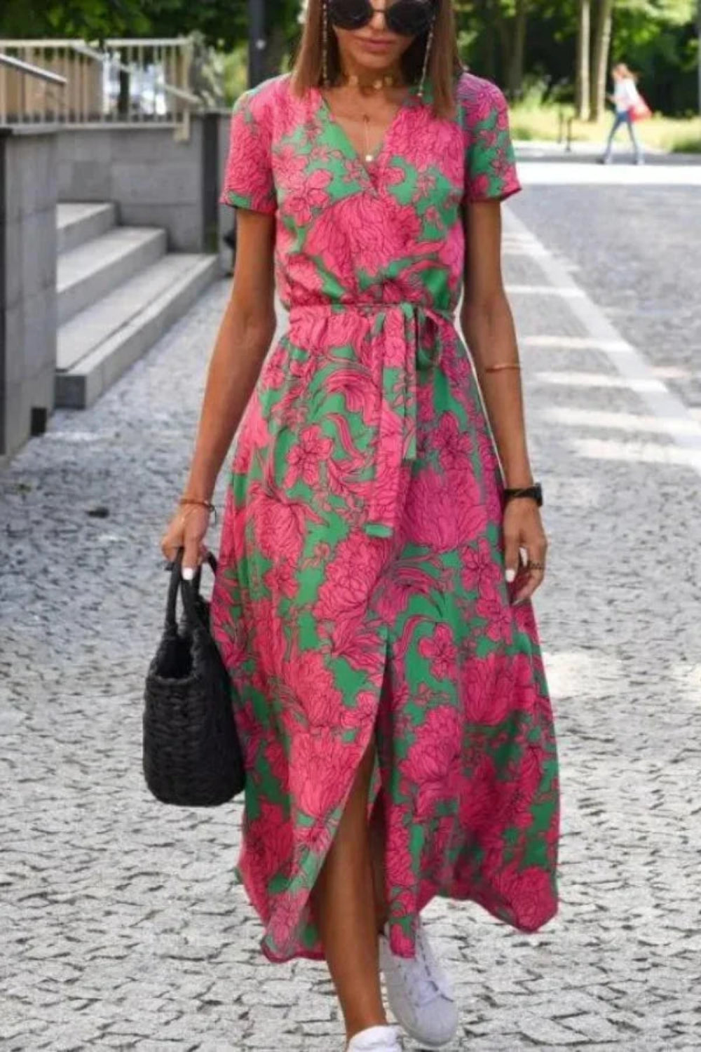 Model wearing Kouvr Fashion pink floral midi wrap dress walking on a cobblestone street