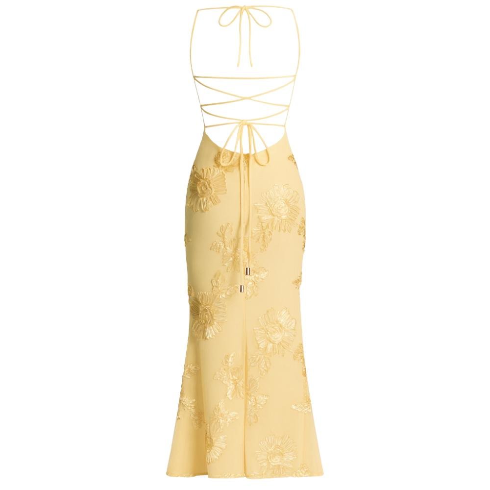 A model viewed from the back wearing the Kouvr Fashion Aphaea Gown, a backless yellow mermaid dress with 3D floral embroidery and an adjustable lace-up corset detail