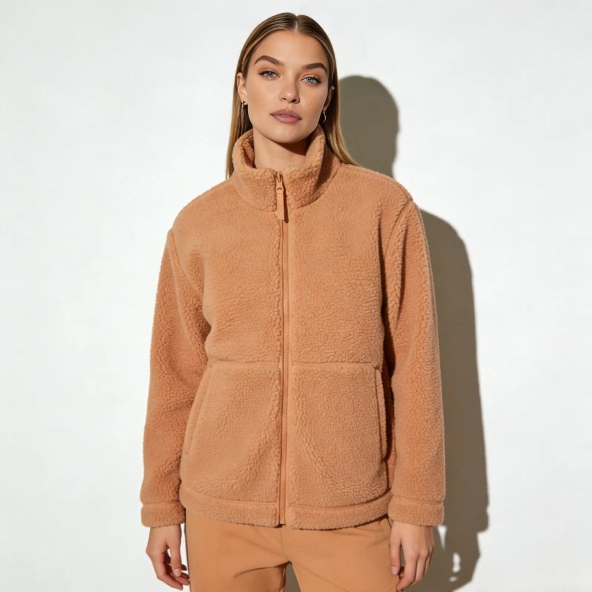 Model wearing the Kouvr Fashion women's apricot sherpa fleece jacket, showcasing its full-zip front and high-neck collar.