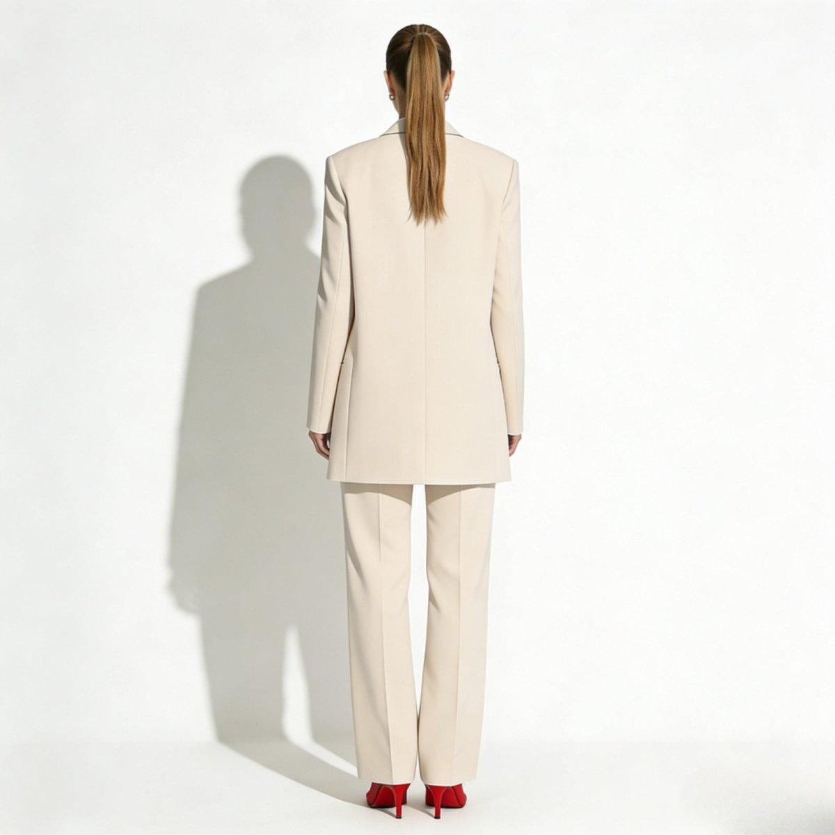 Back view of the Kouvr Fashion apricot women's suit, highlighting the expert tailoring of the longline blazer and the drape of the straight-leg pants.