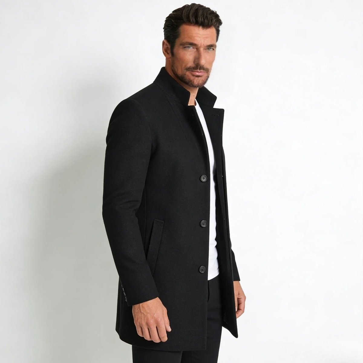 Side profile of a male model in a Kouvr Fashion slim fit black wool overcoat, showing the tailored silhouette and mid-length cut.