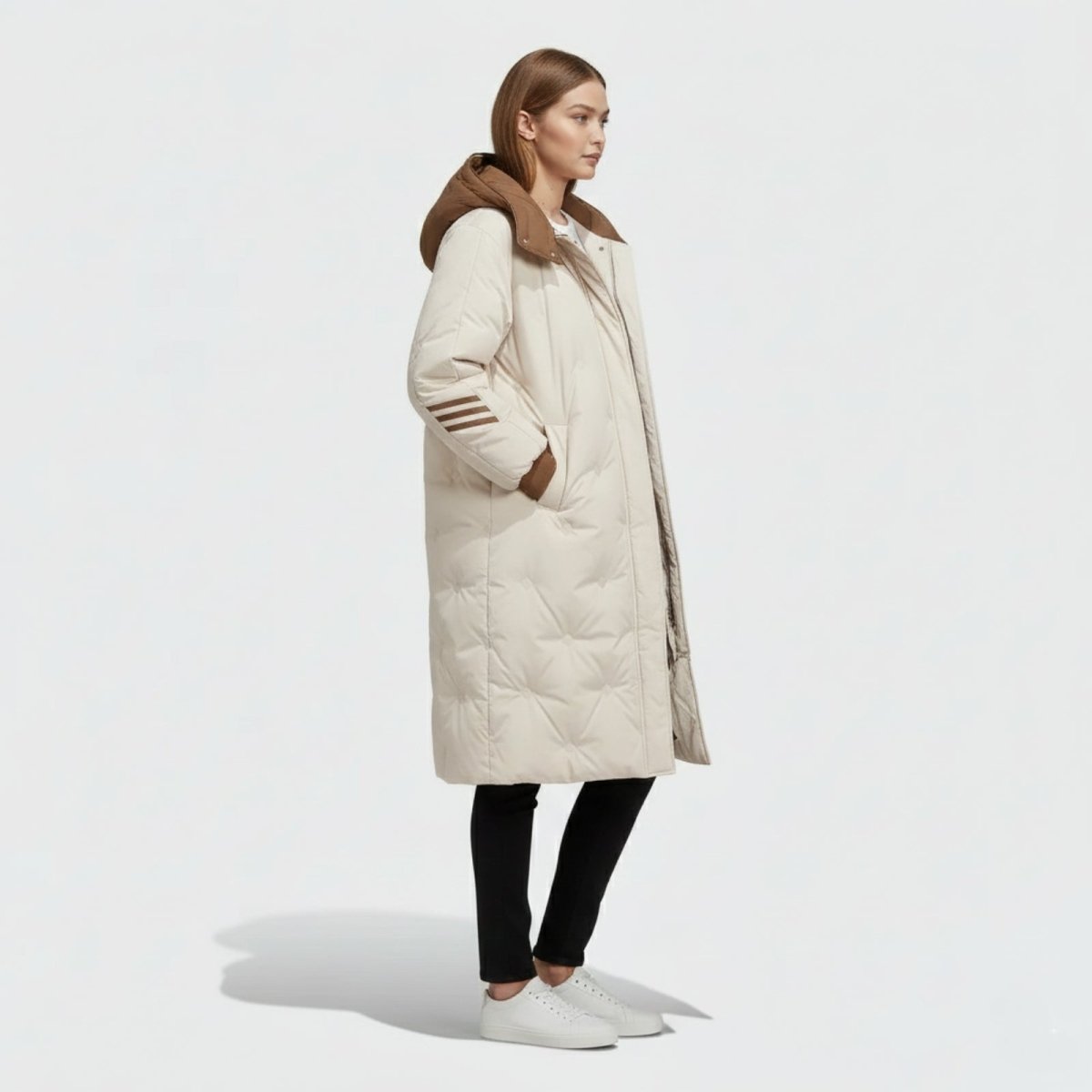 Side profile view of a woman wearing the Kouvr Fashion Arianne oversized long down parka, showcasing its knee-length and quilted texture.