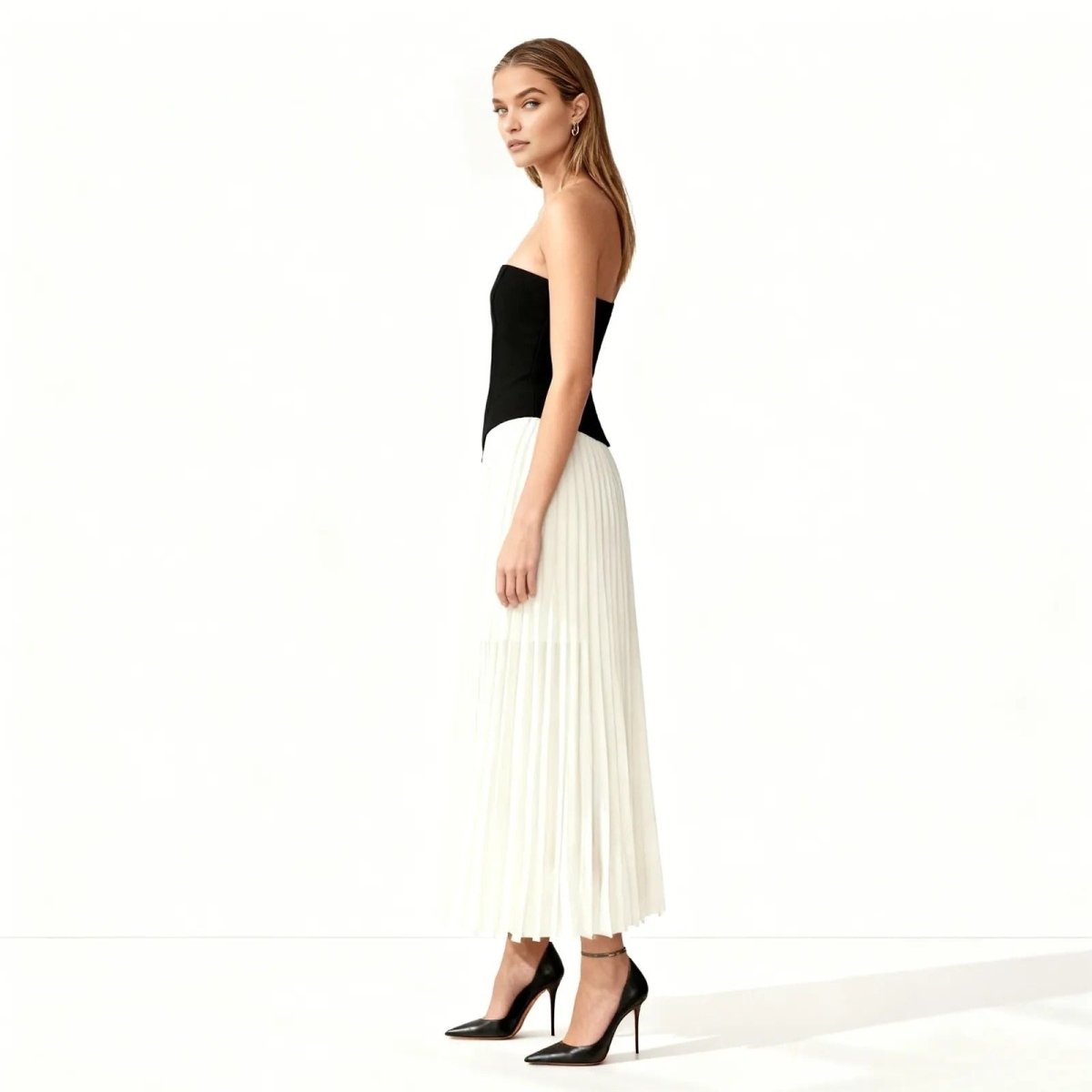 Woman wearing a black strapless top and white pleated skirt on a white background