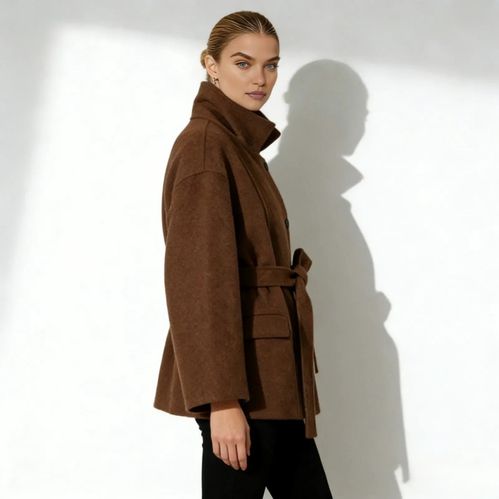 Side profile of a model in the Kouvr Fashion brown wool jacket showing the sculptural high collar and sleeve shape.