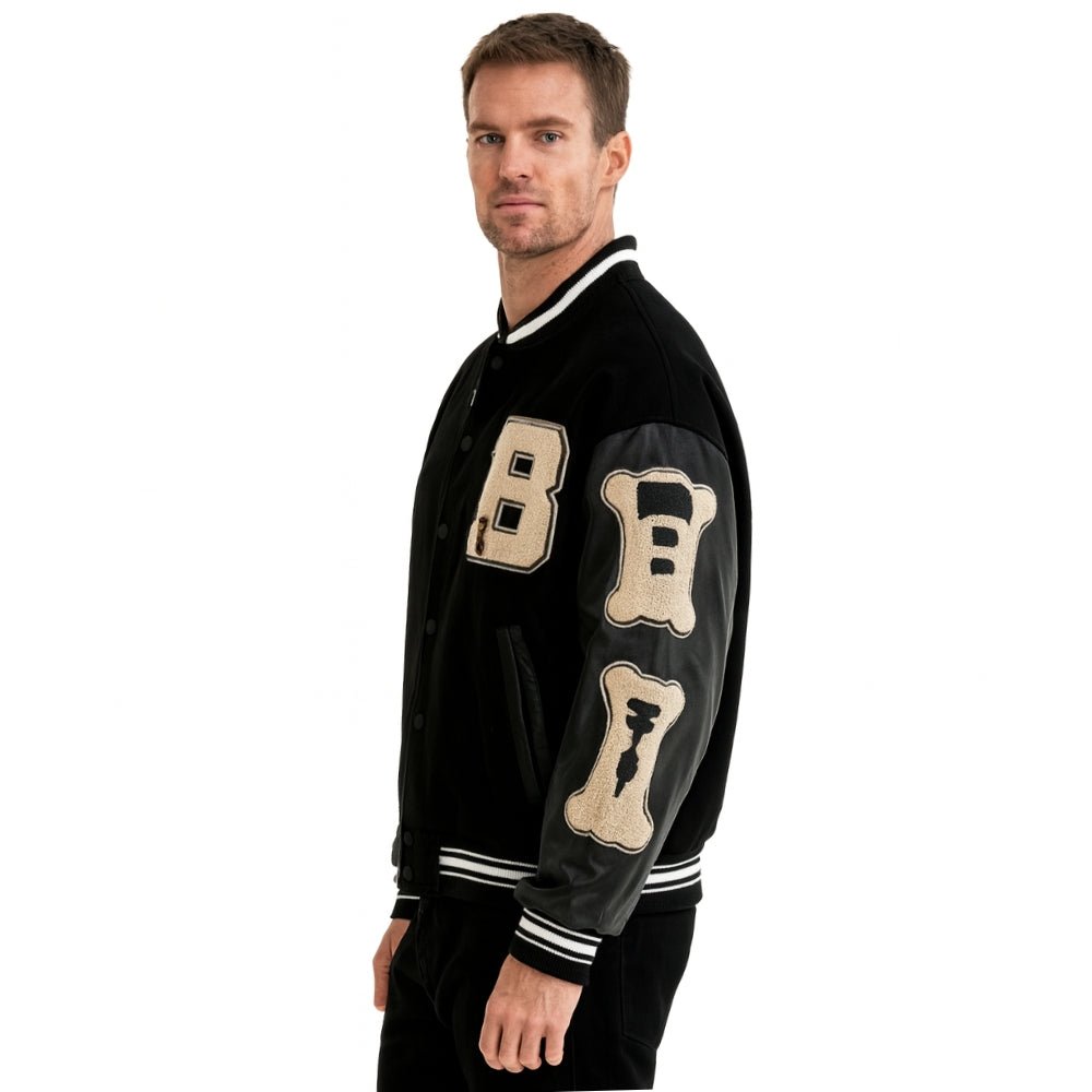 Man wearing a black Kouvr varsity jacket with beige lettering on a white background
