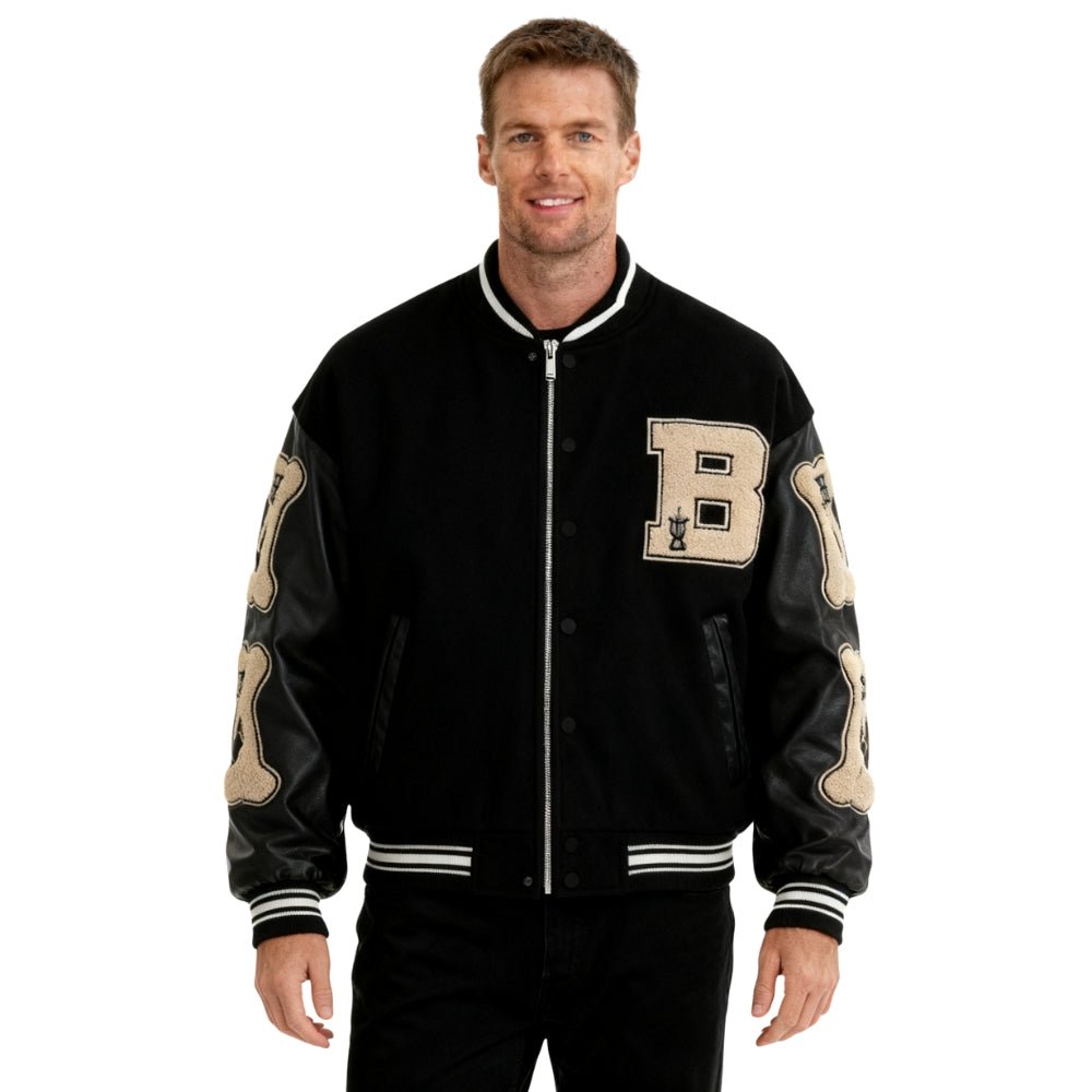 Man wearing a black and beige Kouvr varsity jacket with letter 'B' on a white background