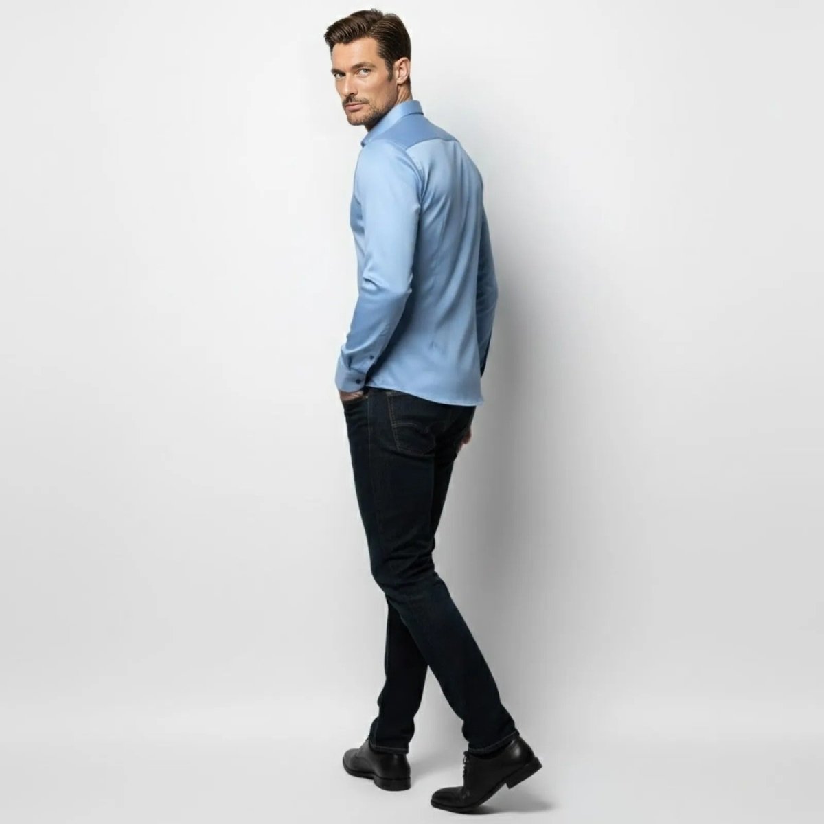 Model looking over his shoulder while wearing the light blue Kouvr Fashion men's dress shirt, displaying the tapered back and fit.