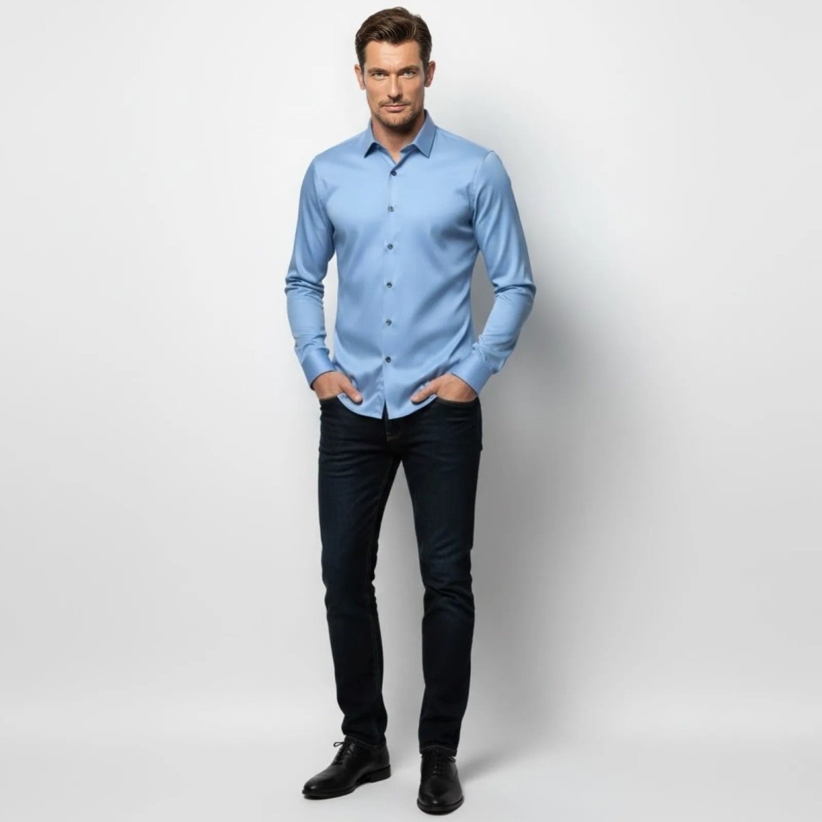 Male model wearing the Kouvr Fashion light blue slim fit performance dress shirt with dark jeans, showing the full outfit from the front.
