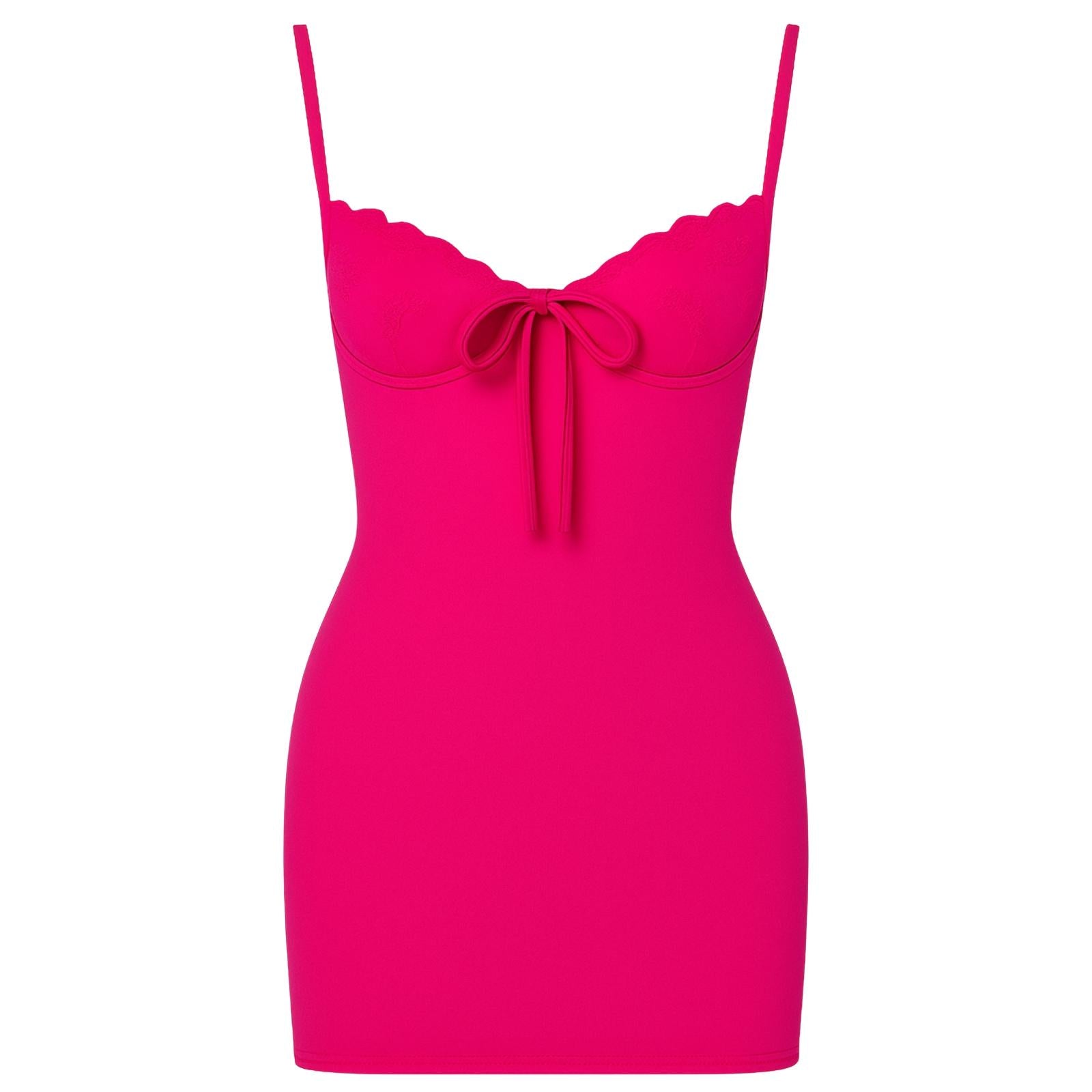 Woman wearing a rose red kouvr dress with thin straps on a white