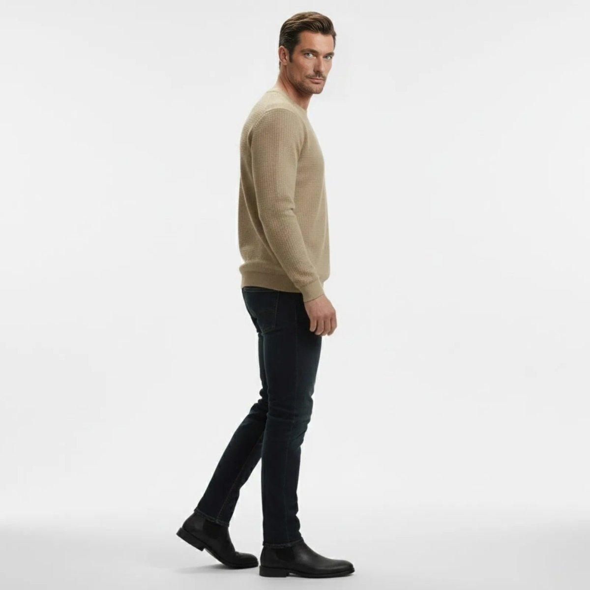 Side profile of a man walking in a khaki waffle knit sweater, showcasing the slim fit and texture of the knitwear.