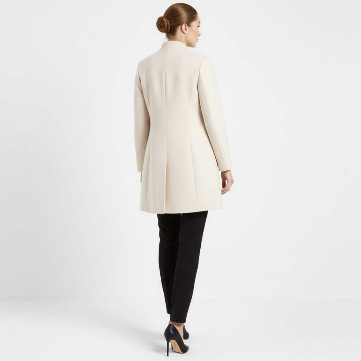 Back view of the Kouvr Fashion cream coat, highlighting the tailored princess seams and elegant inverted pleat detail.