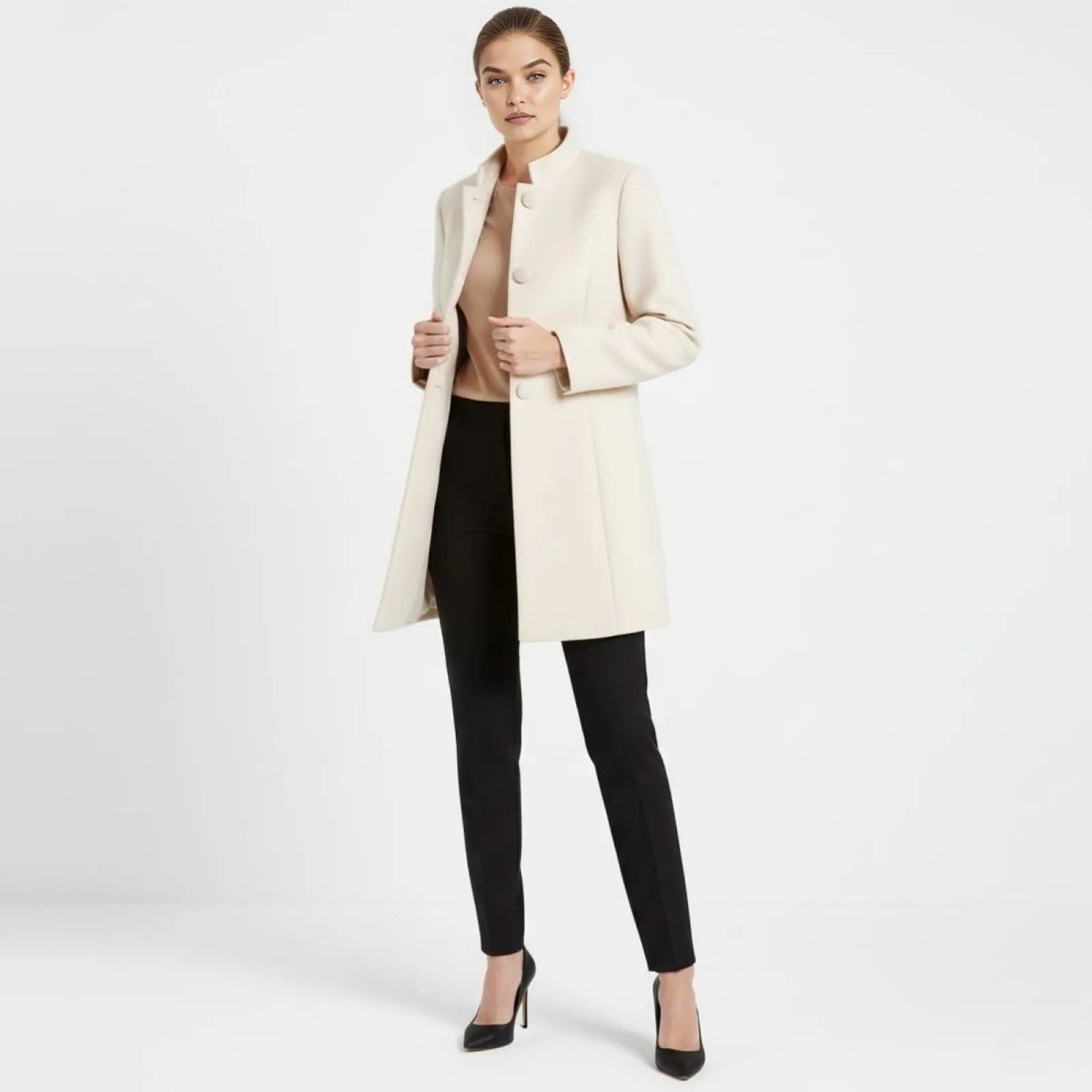 Model wearing the Kouvr Fashion cream funnel neck wool coat, styled with black tailored trousers and black high heels against a white background.