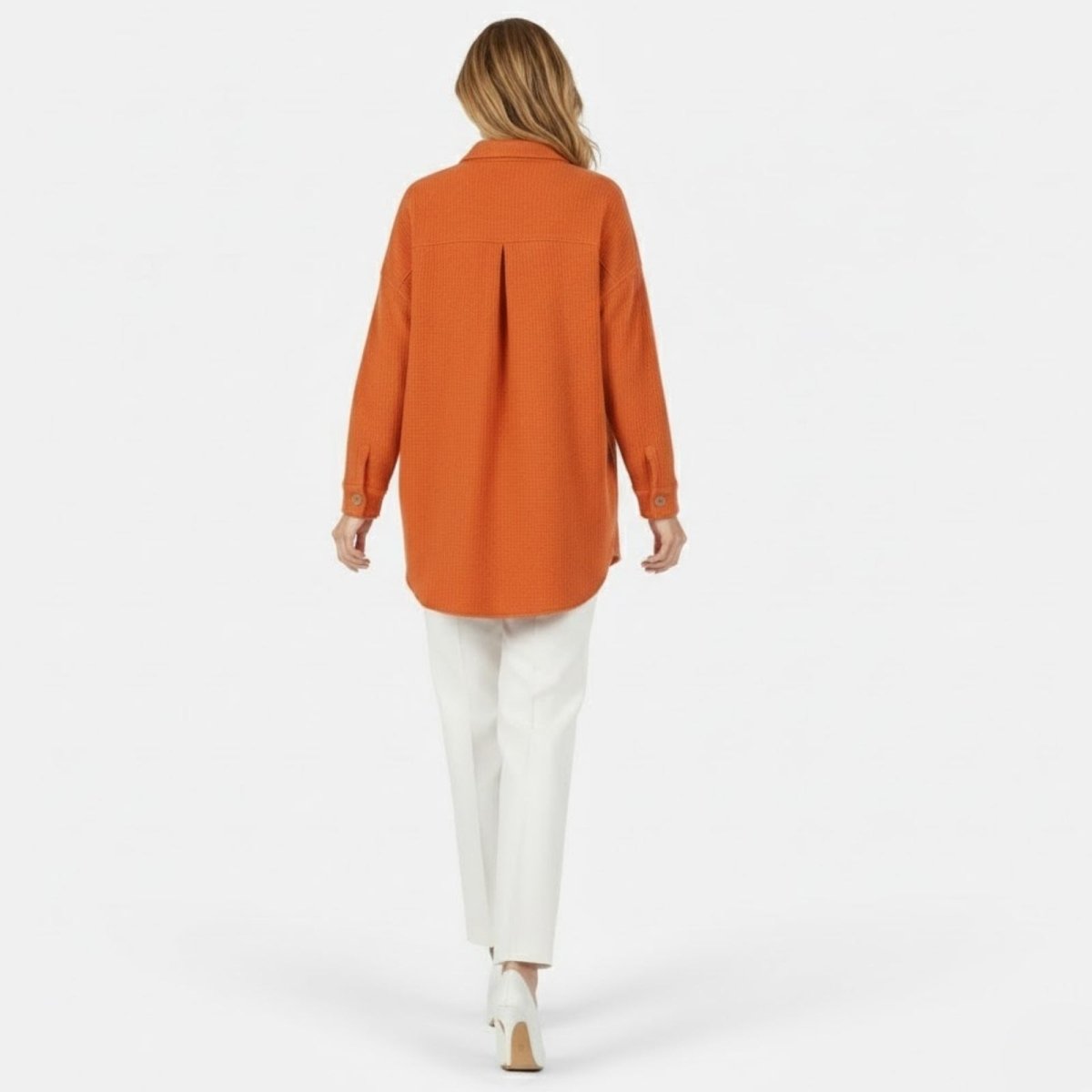 Back view of a woman wearing the burnt orange shacket, showcasing the back yoke, box pleat, and curved shirttail hem detail.