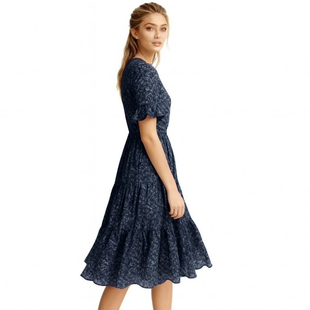 Woman wearing a navy kouvr floral dress on a white background