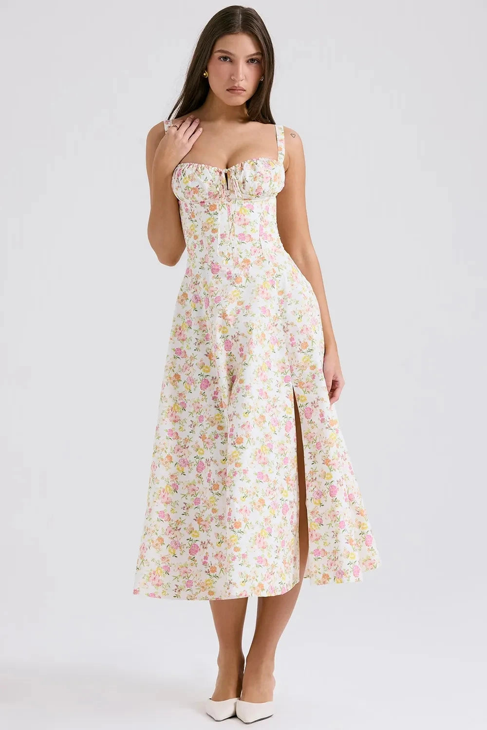 Model wearing Kouvr Fashion Eloise floral corset midi dress in white with pink and yellow flowers, showing the lace-up bustier and A-line skirt