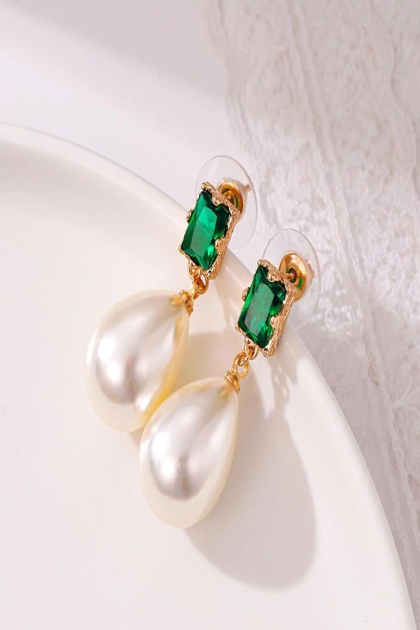 Earrings Kouvr with green gemstones and pearl-like droplets on a white surface