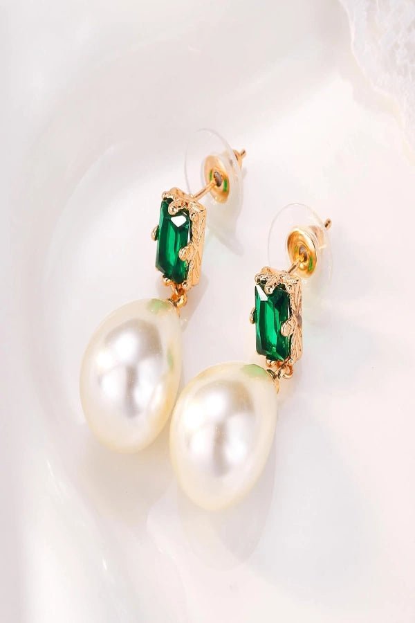 Pearl Kouvr earrings with green gemstones on a white background