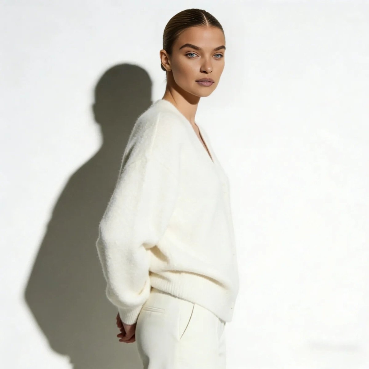 Side profile of a model showing the relaxed, oversized fit of the Kouvr Fashion v-neck cardigan in white