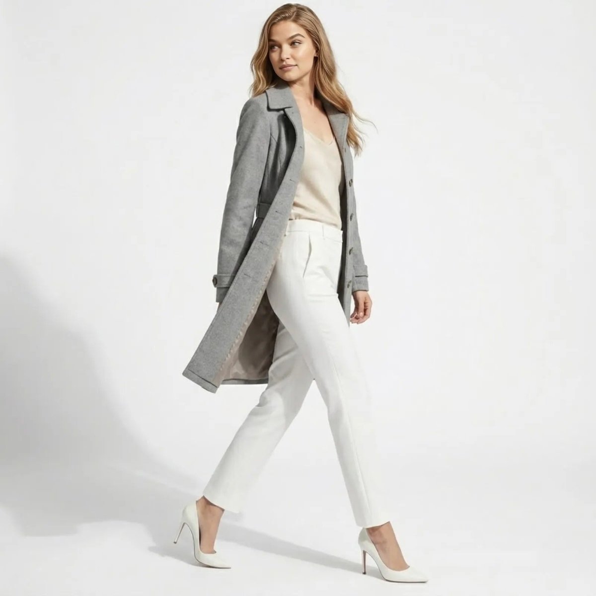 Woman walking and looking over her shoulder in a knee-length grey single-breasted wool coat, showing its elegant movement and drape.