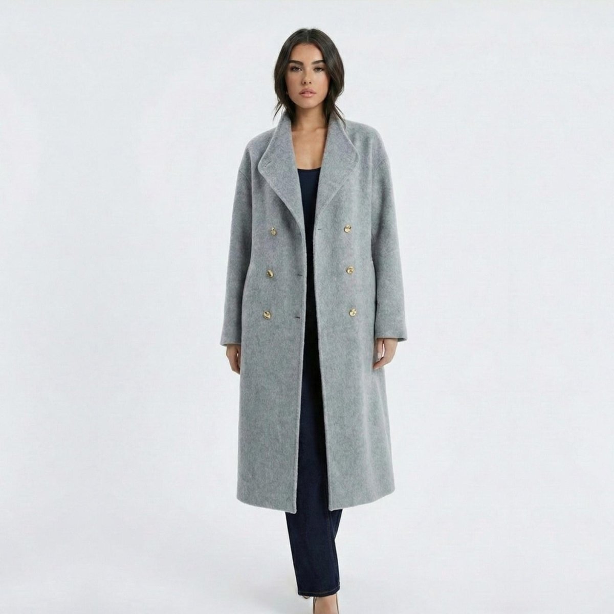 Madison Beer wearing the Maddie long grey wool-blend coat from Kouvr Fashion open, showing the notched lapel and double-breasted gold buttons.