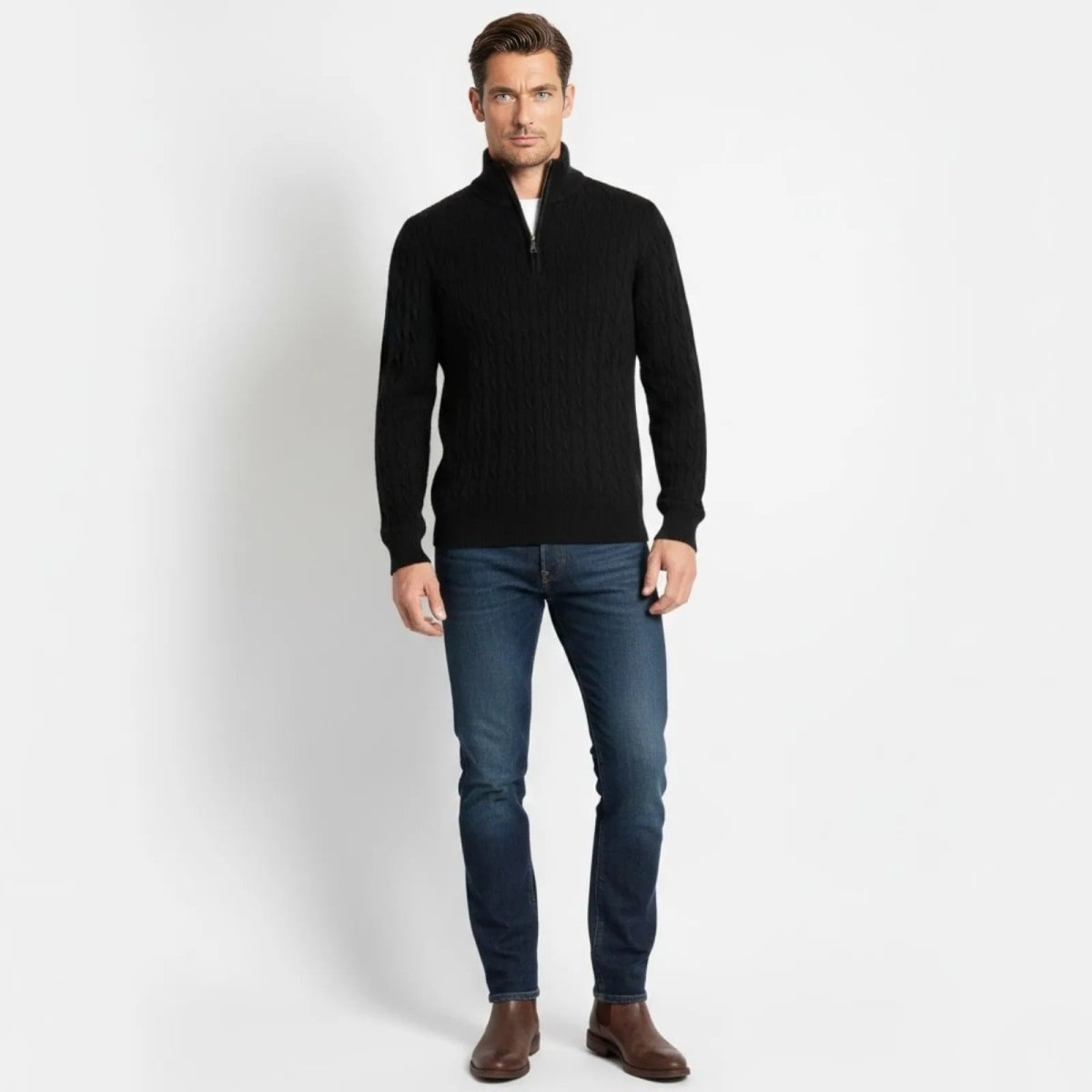 Model wearing the Kouvr Fashion men's black cable-knit half-zip sweater, viewed from the front, styled with dark denim jeans and brown leather boots.
