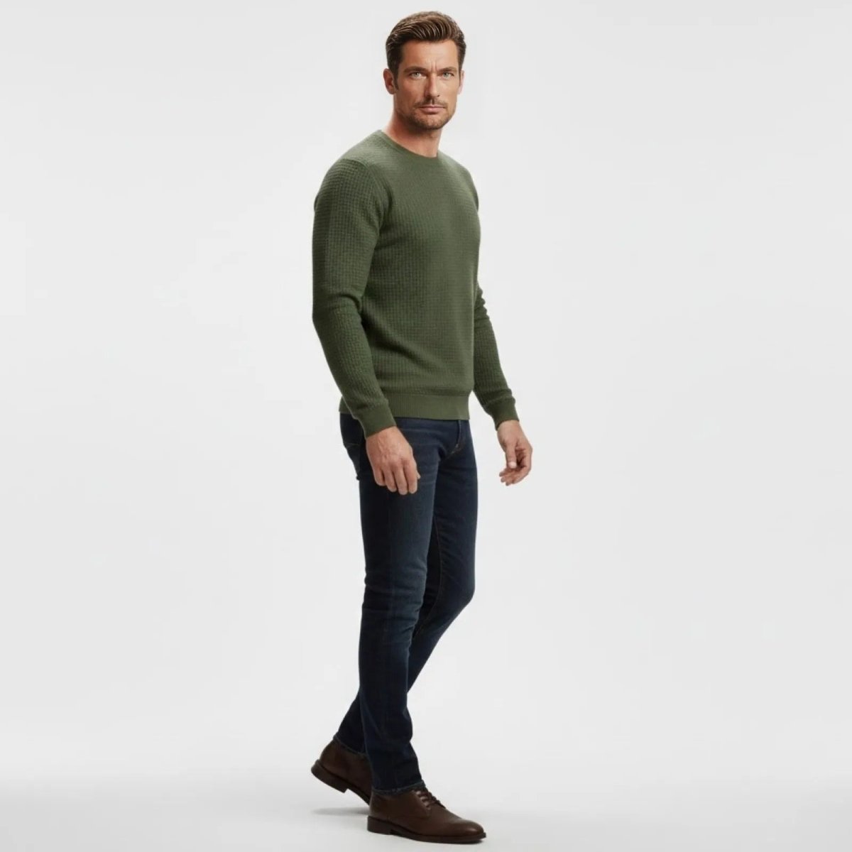 Side profile of a male model wearing the Kouvr Fashion textured crewneck sweater in olive green with dark wash jeans.