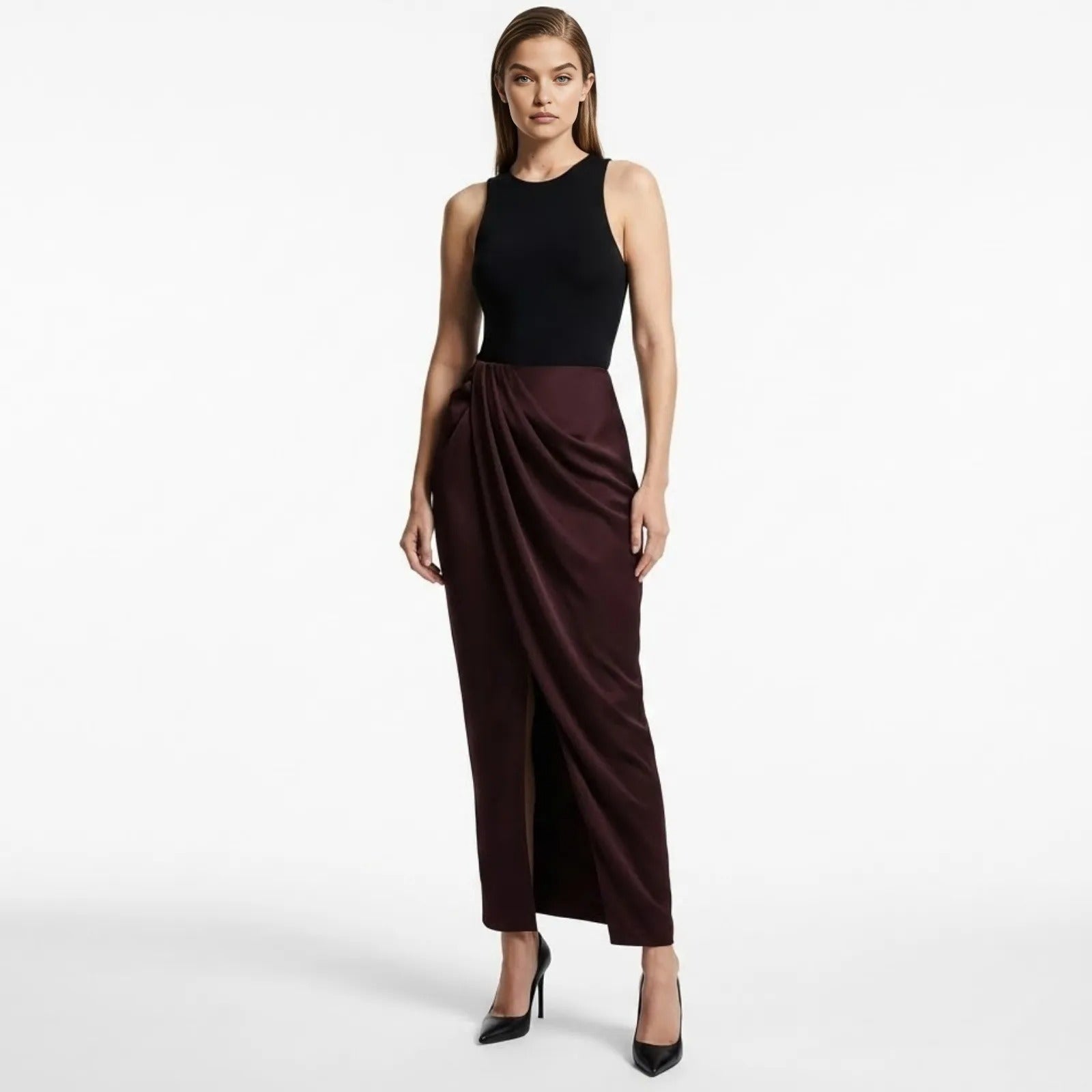 Model wearing Kouvr Fashion's Ourania high-waist draped sarong pants in deep aubergine satin, styled with a black tank top and heels.