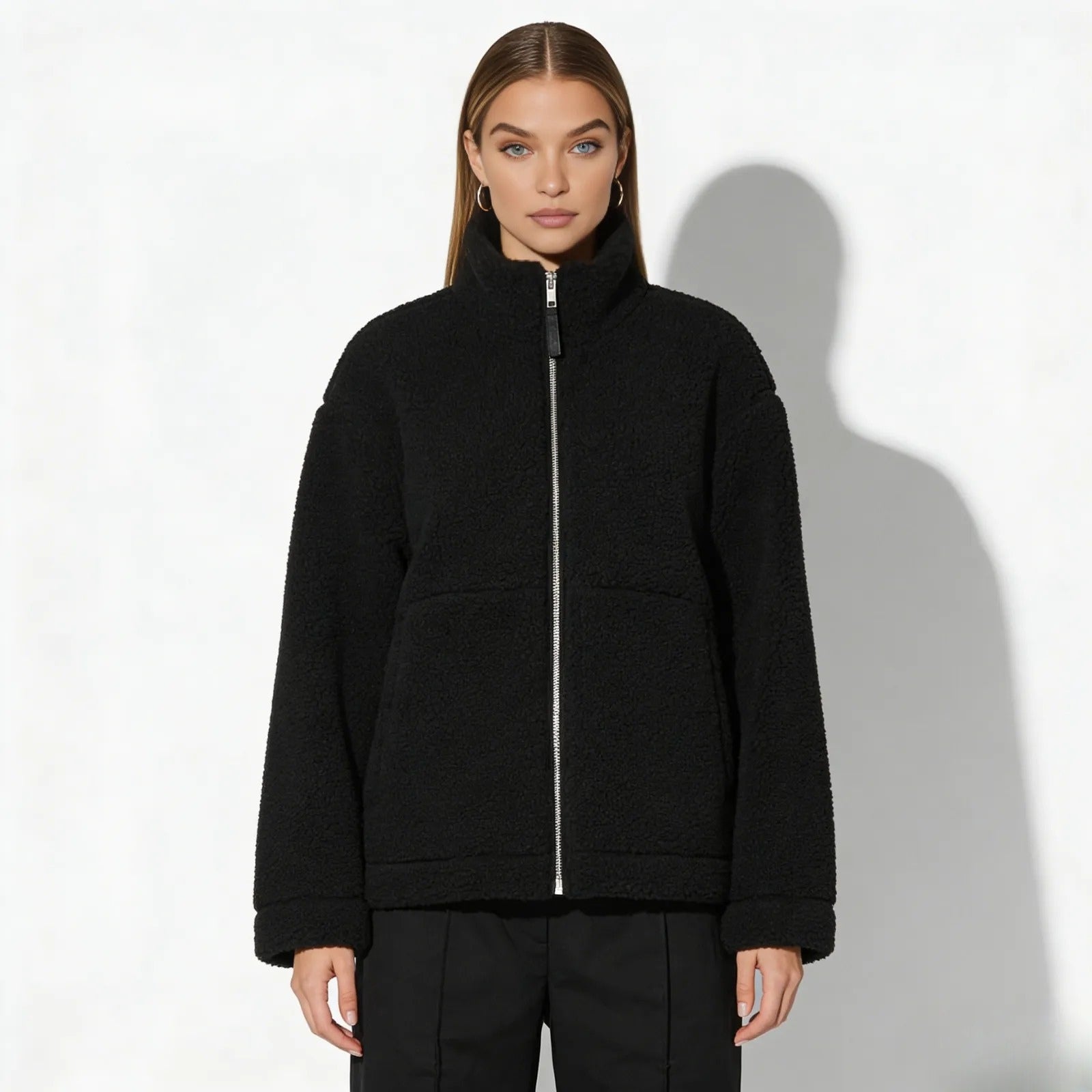 Model wearing the Kouvr oversized black sherpa fleece jacket with a high neck, showcasing its relaxed fit from the front against a white background.