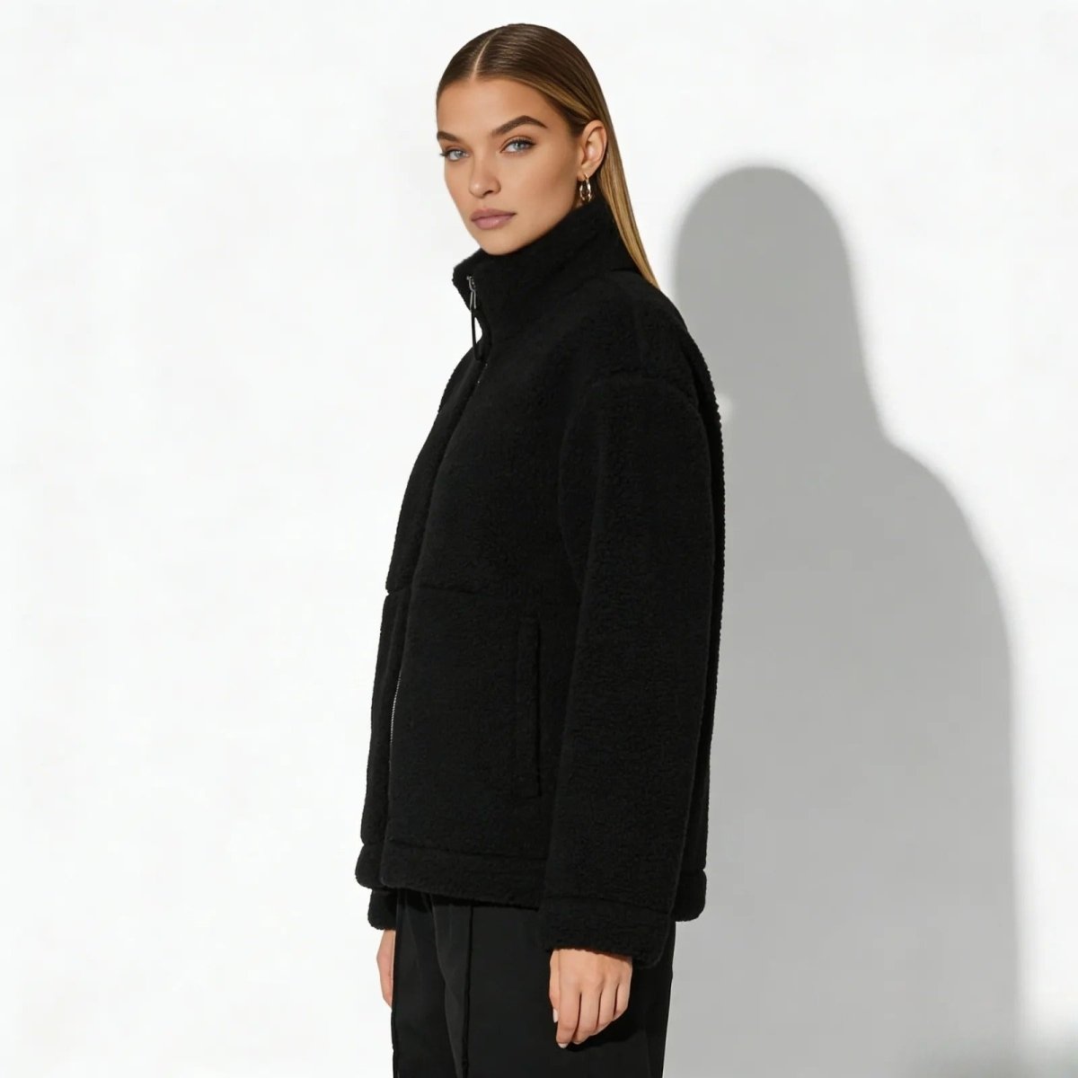 Side profile of a model in the Kouvr oversized black teddy fleece jacket, highlighting the drop-shoulder design and sleeve volume.