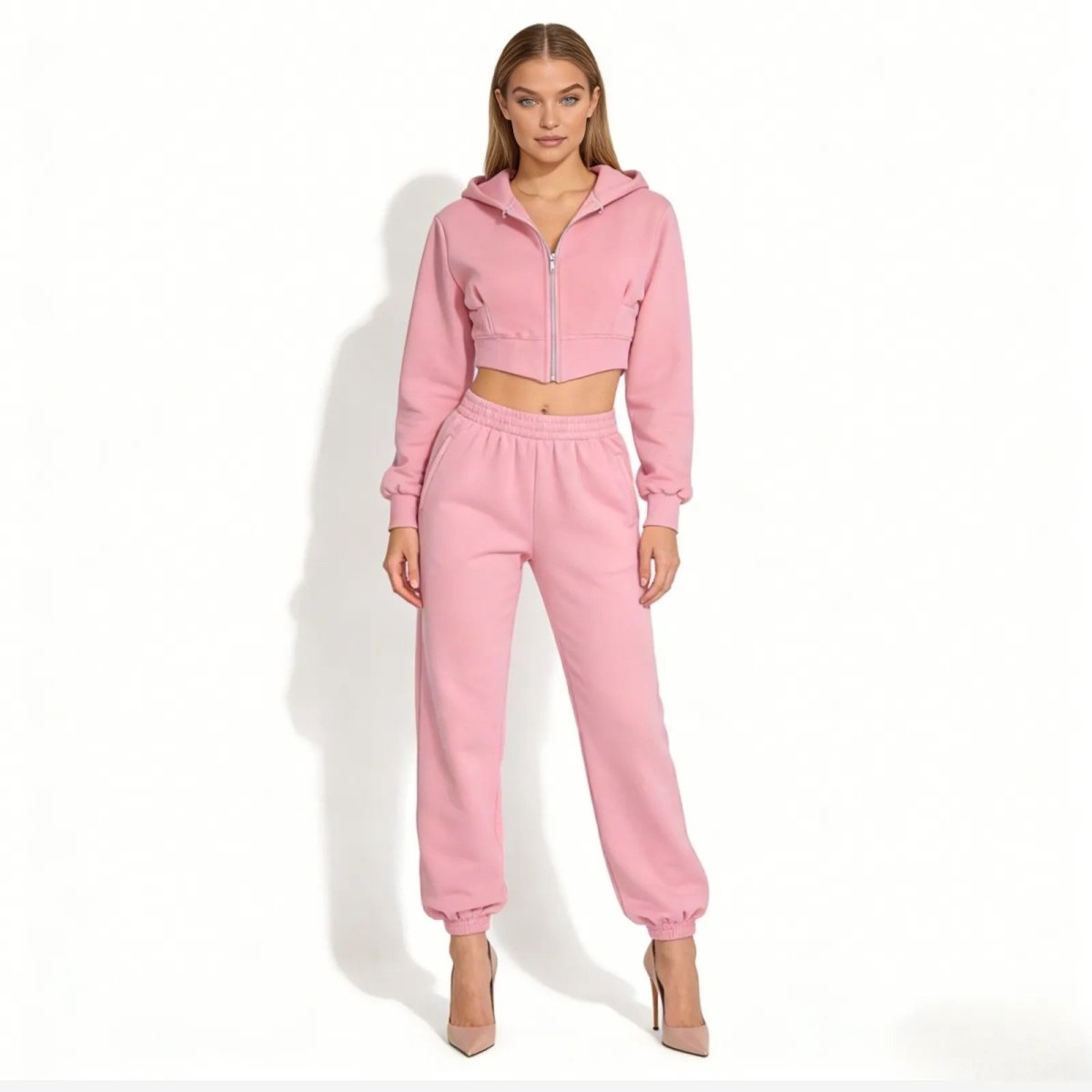 Model wearing the Kouvr Fashion pink two-piece sweatsuit with cropped zip hoodie and matching joggers, front view.