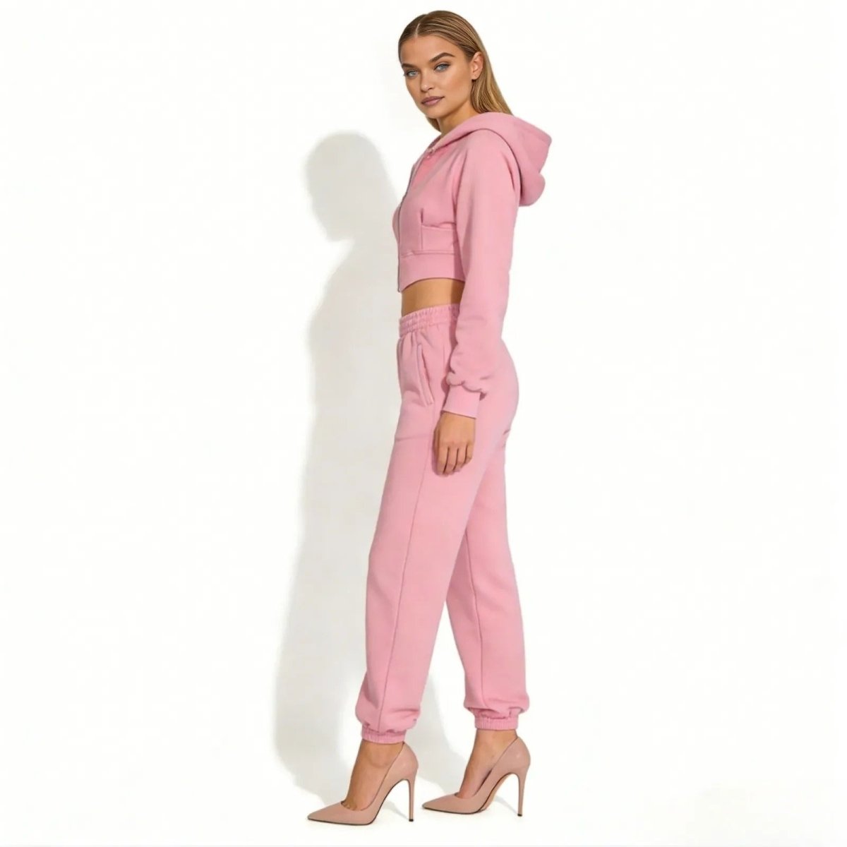Side profile of a model in a pink luxury loungewear set showing the fit of the cropped hoodie and high-waisted joggers.