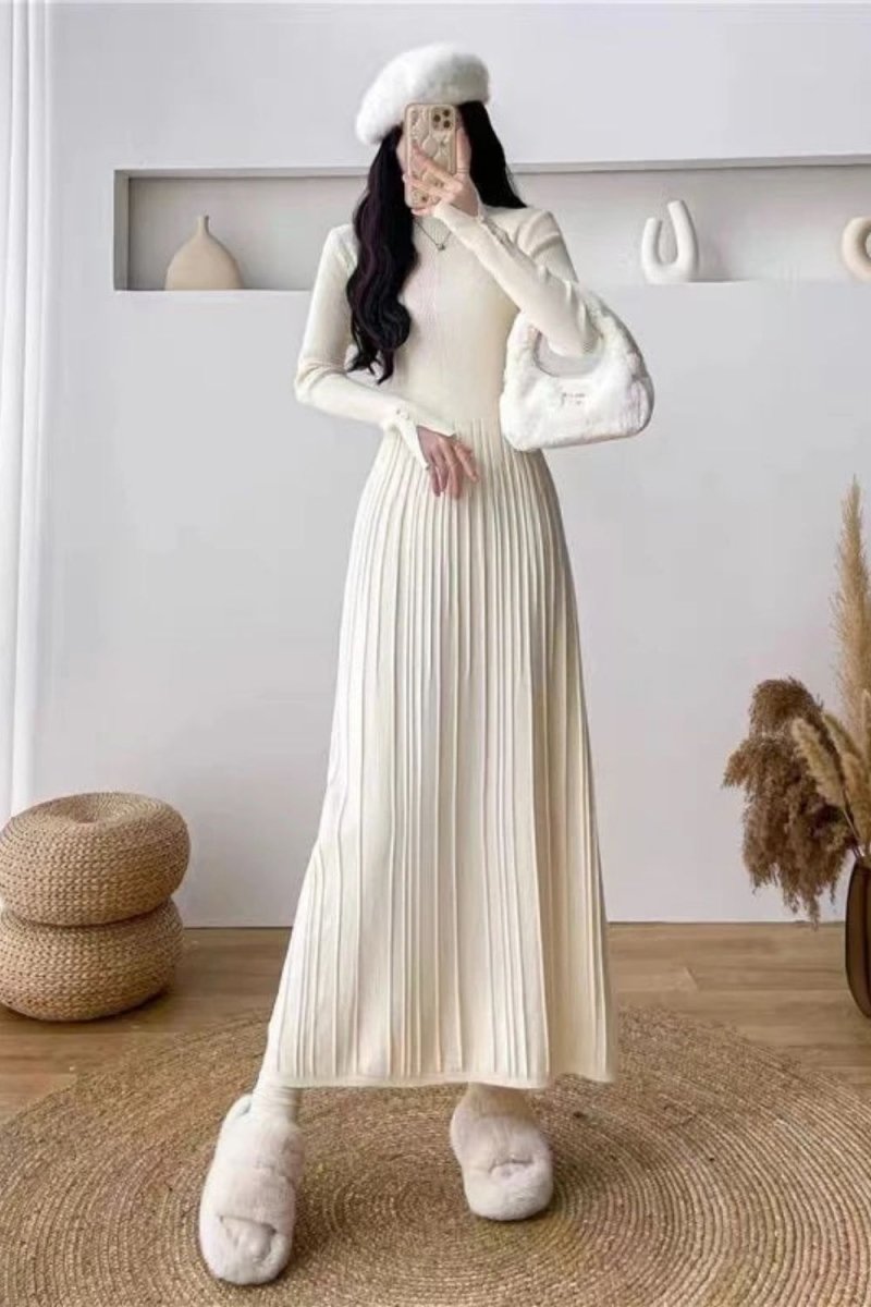 Model wearing the Kouvr Fashion long sleeve pleated knit maxi dress in cream, posing in a minimalist room