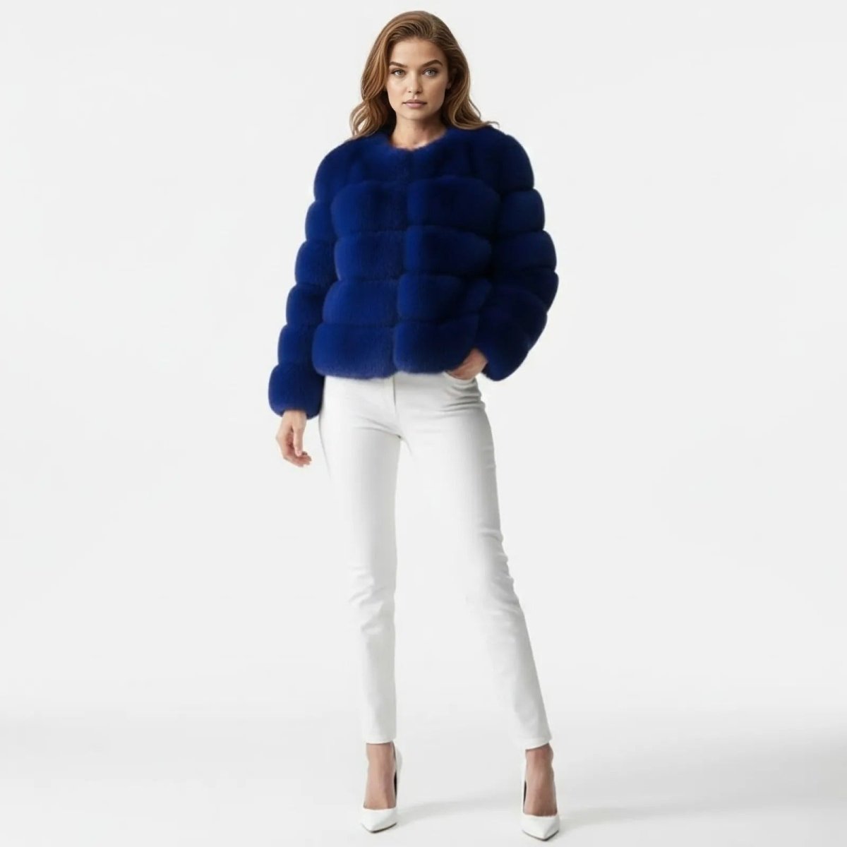 A female model stands facing forward wearing the Kouvr Fashion royal blue faux fur jacket paired with white skinny jeans and white heels.