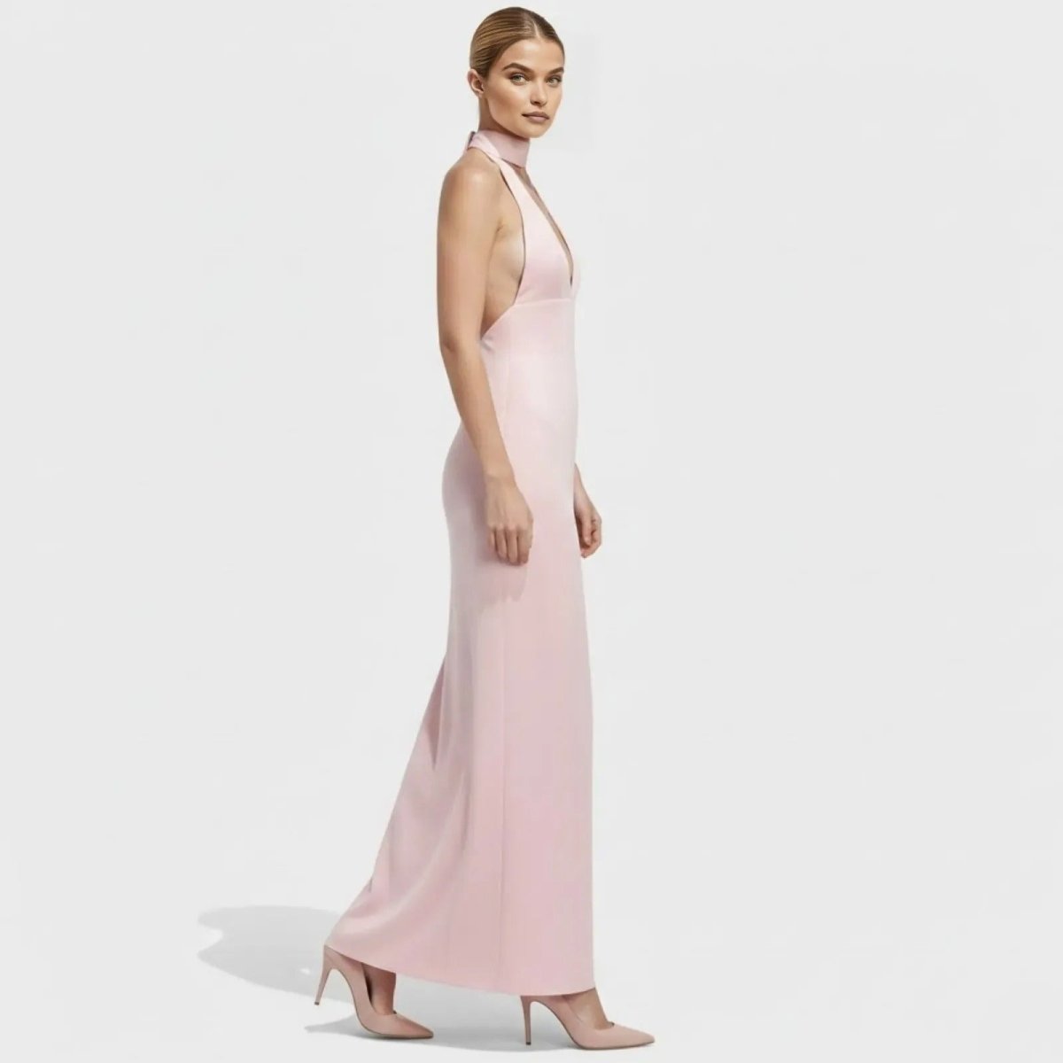 Side profile of a model in a light pink satin evening gown by Kouvr Fashion, highlighting the open side and sleek, body-skimming fit.