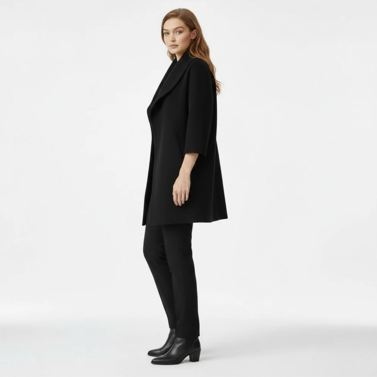 Side profile of a model wearing the Kouvr Fashion black 3/4 sleeve cocoon coat to show its relaxed silhouette and length.