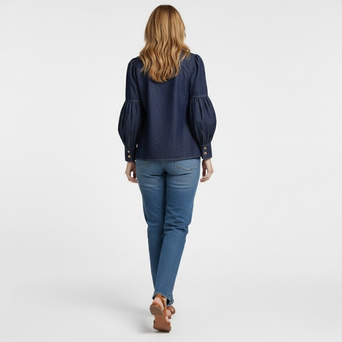 Back view of a model in the Kouvr Fashion dark indigo denim blouse, highlighting the sleeve construction and clean back panel.